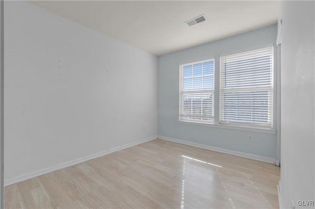 empty room featuring light wood-style floors, visible vents, and baseboards