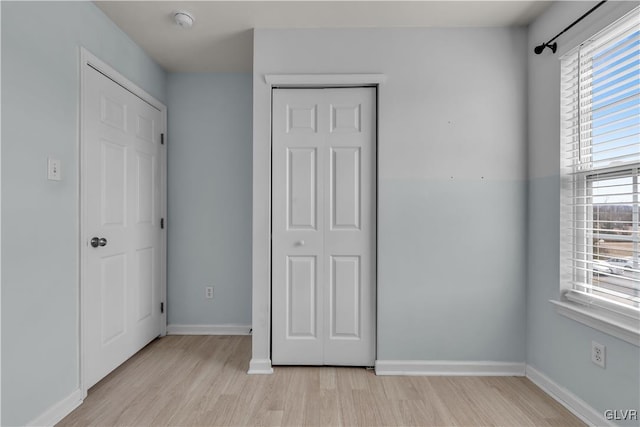 unfurnished bedroom with light wood finished floors, a closet, and baseboards