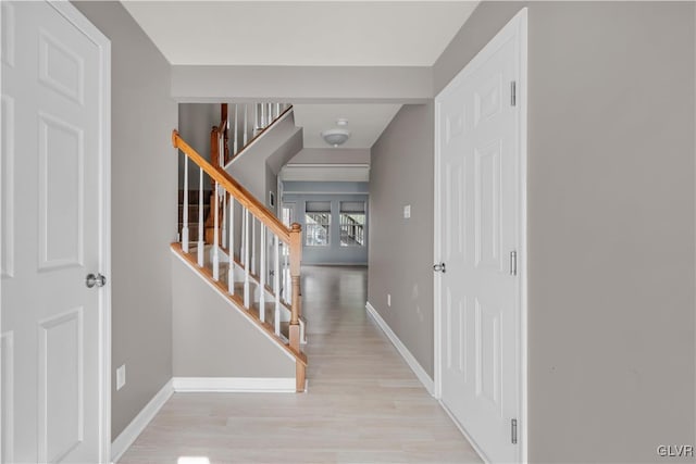 hall with stairway, light wood-style flooring, and baseboards