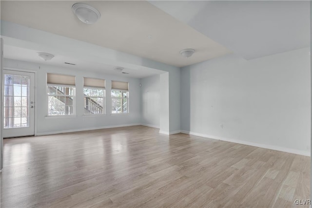 unfurnished room featuring light wood finished floors, plenty of natural light, and baseboards