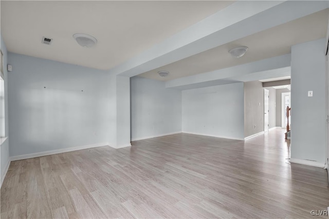 unfurnished room featuring visible vents, light wood-style flooring, and baseboards