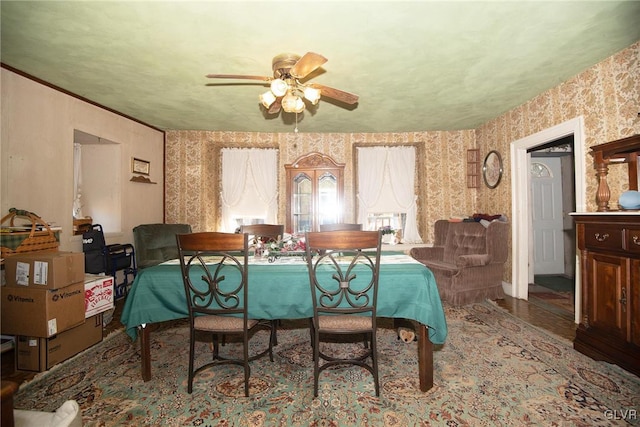 dining area featuring crown molding, a ceiling fan, and wallpapered walls