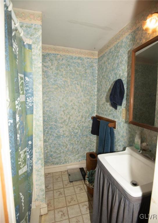 bathroom with wallpapered walls, baseboards, and vanity