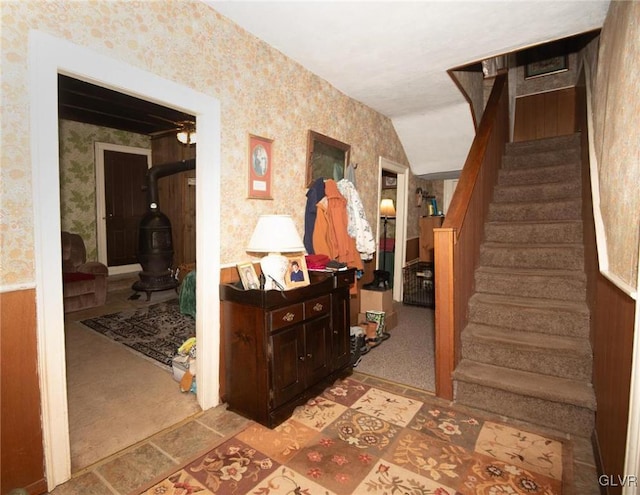 hall with stairs, lofted ceiling, light carpet, and wallpapered walls