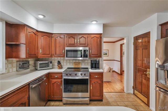 kitchen with stainless steel appliances, light tile patterned flooring, light countertops, and decorative backsplash