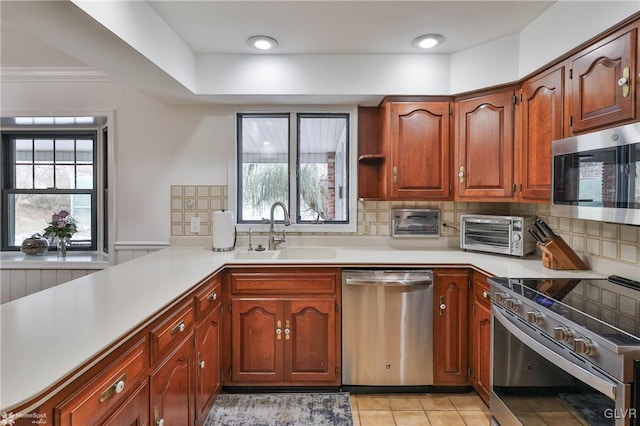 kitchen with a toaster, light countertops, decorative backsplash, appliances with stainless steel finishes, and a sink