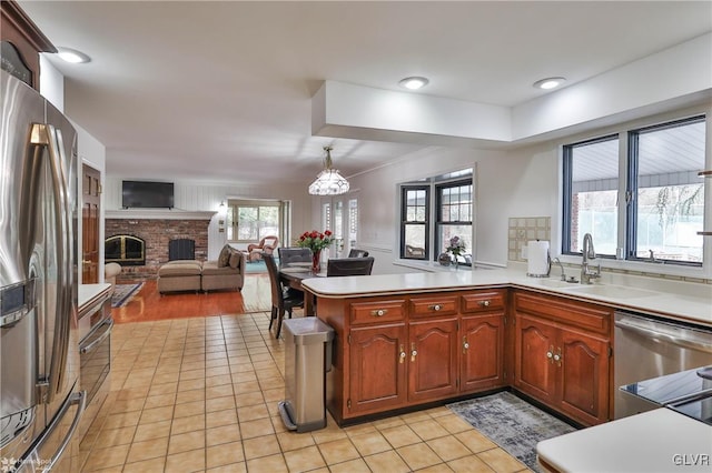 kitchen with stainless steel appliances, hanging light fixtures, a peninsula, and light countertops