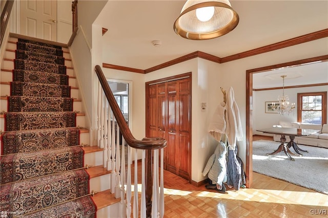 foyer entrance featuring a notable chandelier, stairway, baseboards, and crown molding