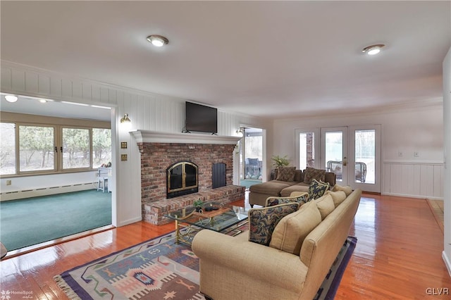 living area featuring a baseboard heating unit, french doors, a fireplace, and light wood-style floors