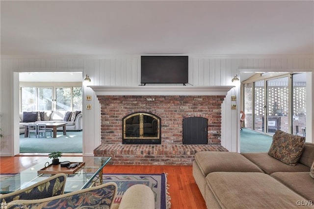 living room featuring ornamental molding, a fireplace, and wood finished floors