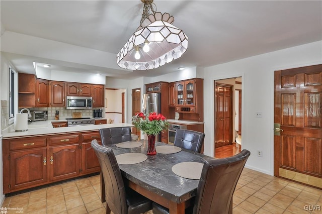 dining area featuring light tile patterned floors, a toaster, and baseboards