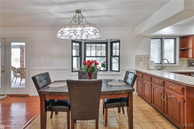 dining area with a wainscoted wall, plenty of natural light, crown molding, and french doors