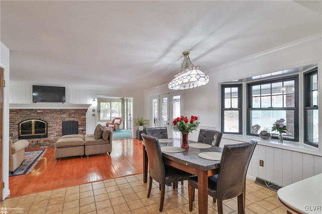 dining room with ornamental molding, light tile patterned flooring, and a fireplace