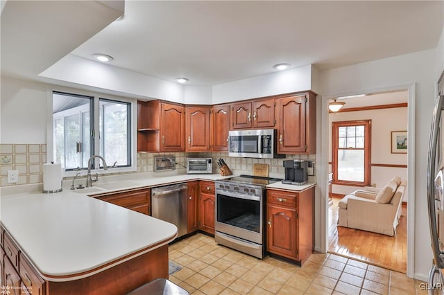 kitchen with a peninsula, stainless steel appliances, a sink, and light countertops