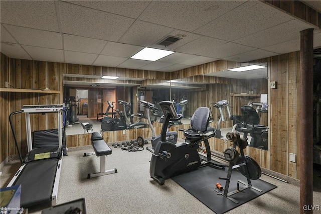 workout area featuring a paneled ceiling, visible vents, and wooden walls