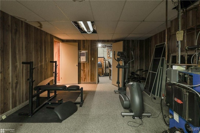 exercise area with a paneled ceiling, wood walls, and a heating unit