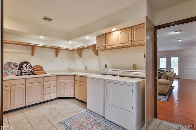 laundry area featuring cabinet space, light tile patterned floors, visible vents, separate washer and dryer, and a sink