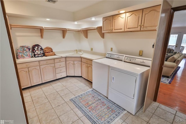 laundry room with light tile patterned floors, washing machine and dryer, a sink, visible vents, and cabinet space