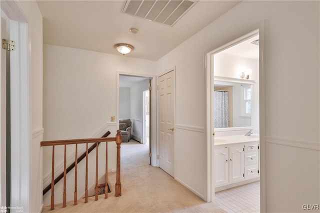 hall featuring light carpet, an upstairs landing, and visible vents