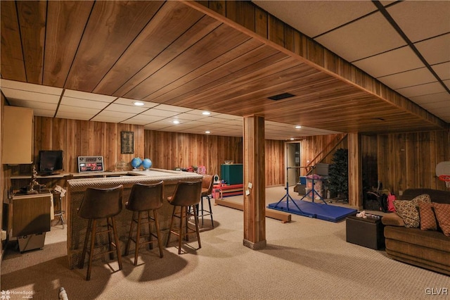 bar featuring recessed lighting, light colored carpet, wooden walls, wood ceiling, and a dry bar