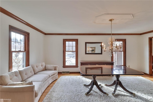 living area with baseboards, visible vents, ornamental molding, an inviting chandelier, and light wood-type flooring