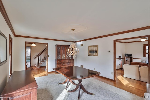 dining area with a notable chandelier, baseboards, stairs, light wood-type flooring, and crown molding