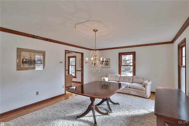 living room with a notable chandelier, ornamental molding, light wood-type flooring, and baseboards