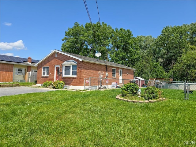 view of property exterior featuring roof mounted solar panels, brick siding, fence, and a lawn