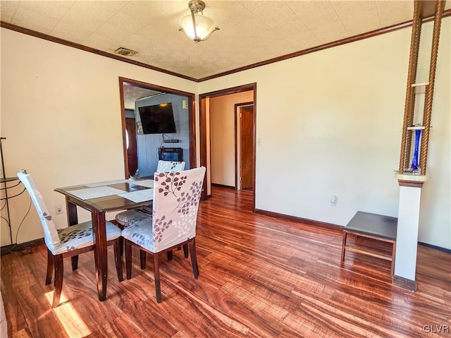 dining space with ornamental molding, wood finished floors, visible vents, and baseboards