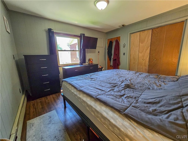 bedroom with dark wood-style floors, a baseboard radiator, and visible vents