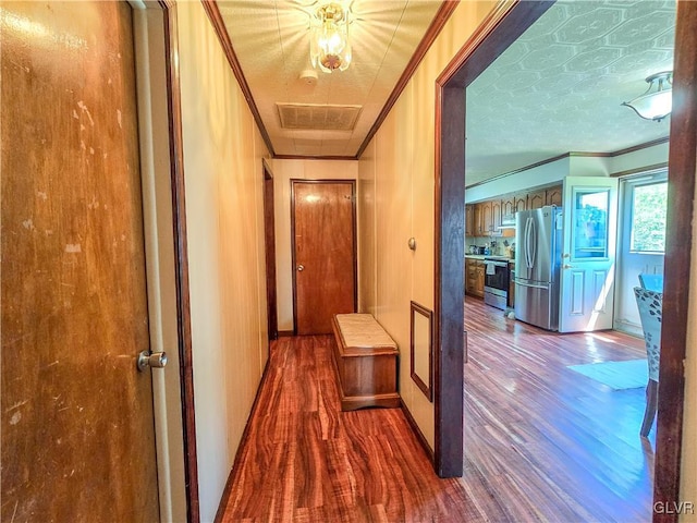 hall with ornamental molding, visible vents, baseboards, and dark wood-style floors