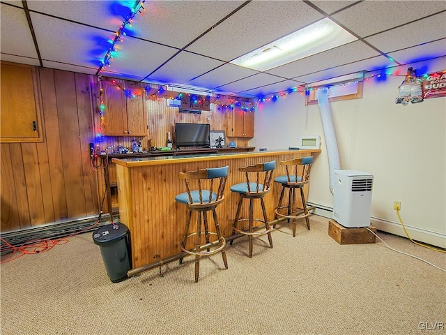 bar featuring wooden walls, light carpet, a drop ceiling, and a dry bar