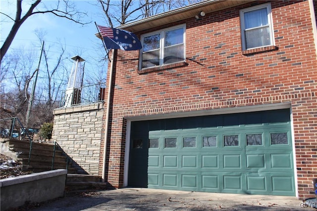 view of side of property with driveway, brick siding, and an attached garage