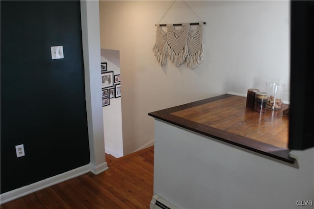 corridor with a baseboard radiator, baseboards, and wood finished floors