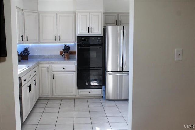 kitchen with dobule oven black, white cabinetry, light countertops, freestanding refrigerator, and tasteful backsplash