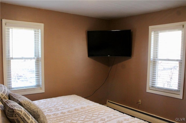 bedroom featuring a baseboard heating unit and multiple windows