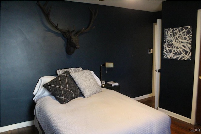 bedroom with dark wood-type flooring and baseboards