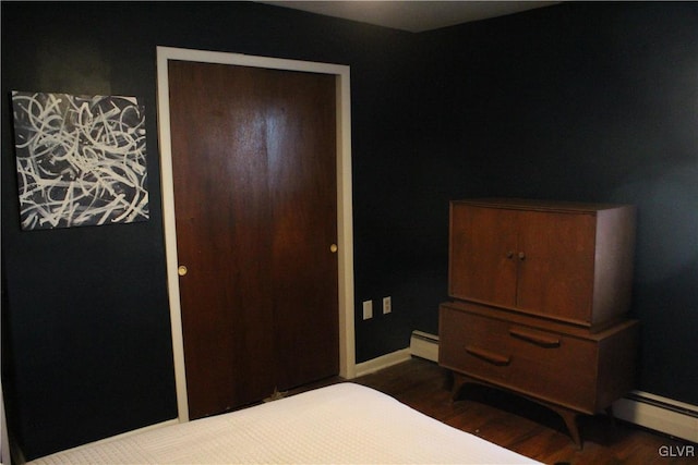 bedroom with a baseboard radiator, baseboards, and wood finished floors