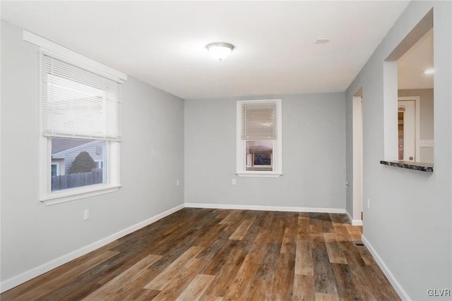 spare room featuring dark wood-style floors and baseboards