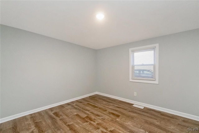 empty room with visible vents, baseboards, and wood finished floors