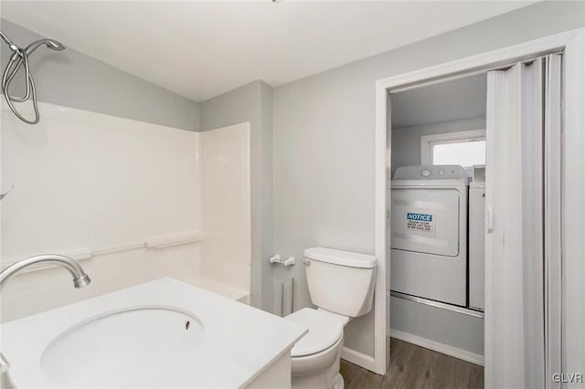 bathroom with a shower, washer and clothes dryer, toilet, vanity, and wood finished floors