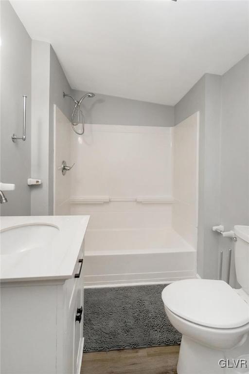 bathroom featuring shower / washtub combination, vanity, toilet, and wood finished floors