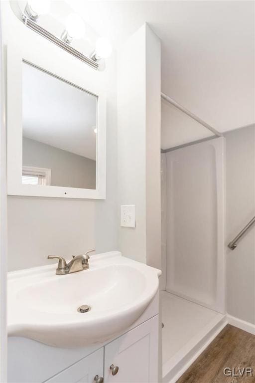 full bathroom with walk in shower, vanity, and wood finished floors