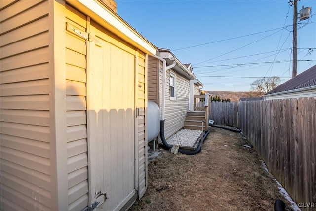 view of side of property featuring heating fuel and fence