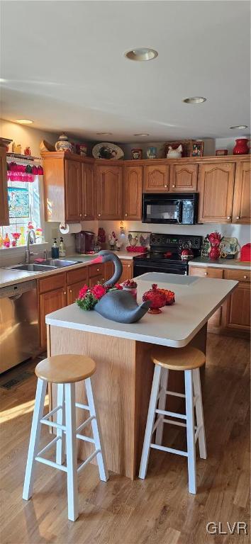 kitchen with a kitchen breakfast bar, black appliances, light countertops, and a center island