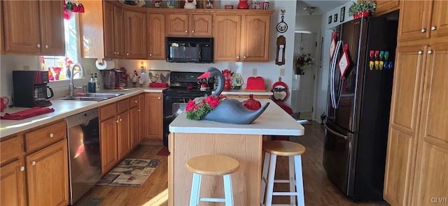 kitchen with a center island, light countertops, a sink, and black appliances