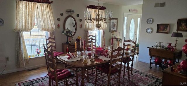 dining area featuring wood finished floors, visible vents, and a notable chandelier