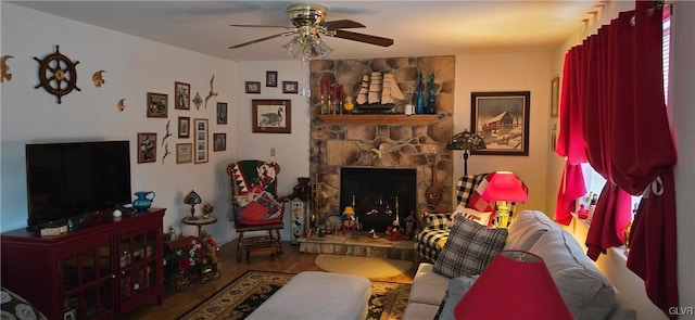 living area with a ceiling fan, a fireplace, and wood finished floors