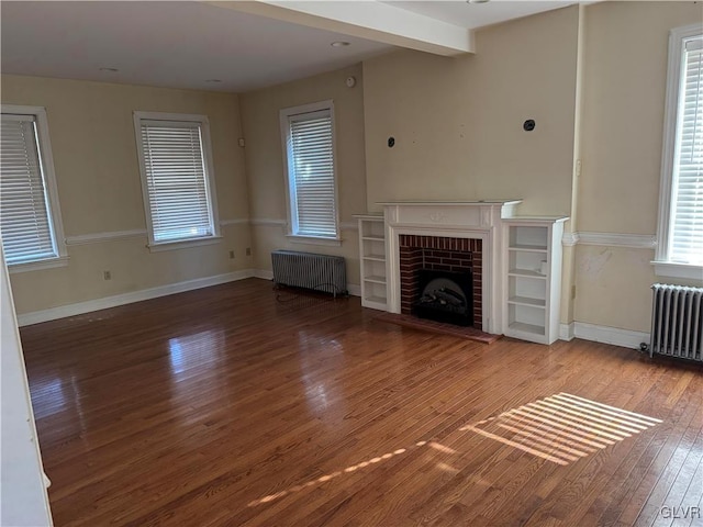 unfurnished living room with radiator heating unit, a fireplace, baseboards, and wood finished floors