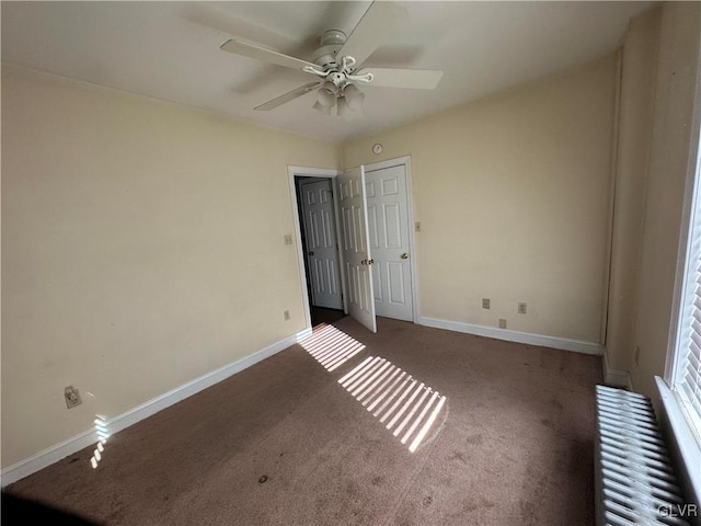 unfurnished bedroom featuring radiator, a ceiling fan, baseboards, and carpet floors